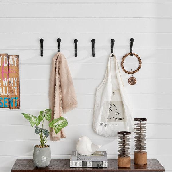 Six Black Cast Iron Railway Spike Wall Mount Hooks above a desk holding a scarf, a canvas bag, and an ornament.