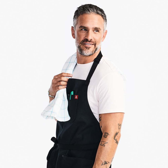 Man wearing Hedley & Bennett Caviar Essential Apron with a towel over his shoulder