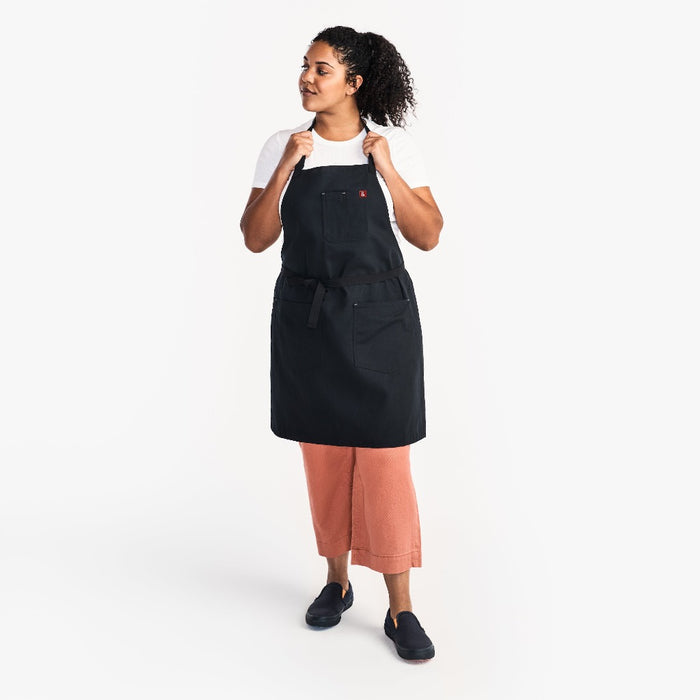 Woman wearing Hedley & Bennett Caviar Essential Apron with her hands on the neck straps