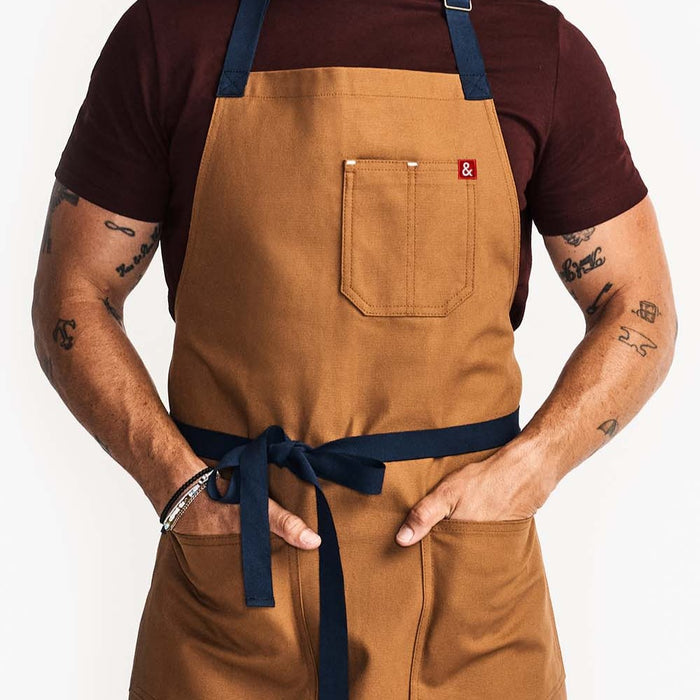 Man with his hands in front pockets of tan apron