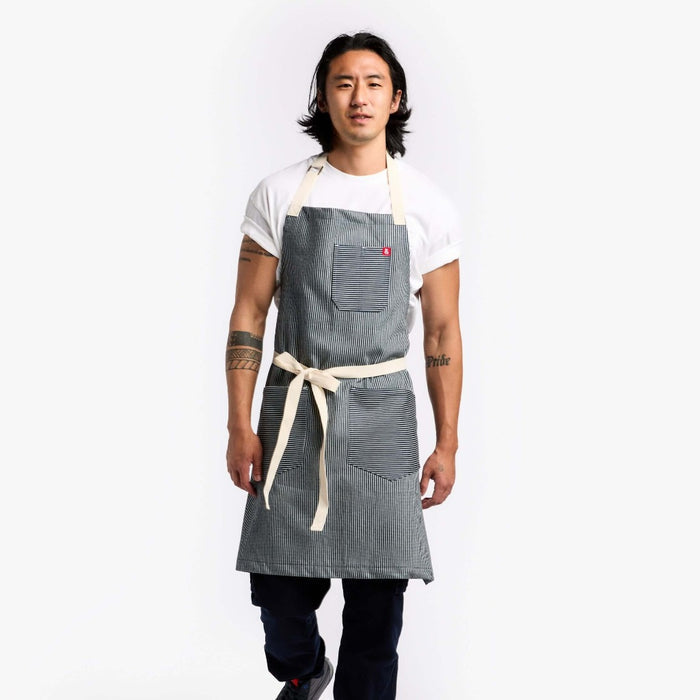 Man wearing striped apron with tattoos and black pants