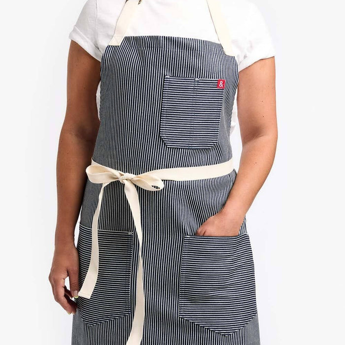 Woman wearing striped apron with her hand in large front pocket