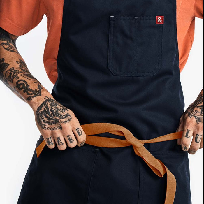 Man with tattoos adjusting front apron straps