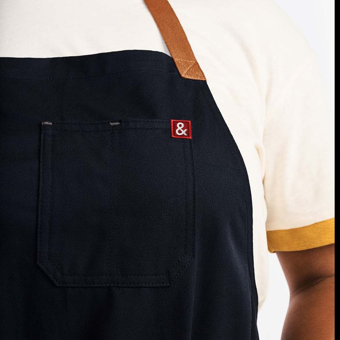 Woman wearing midnight blue apron with tan straps and red Hedley & Bennett logo