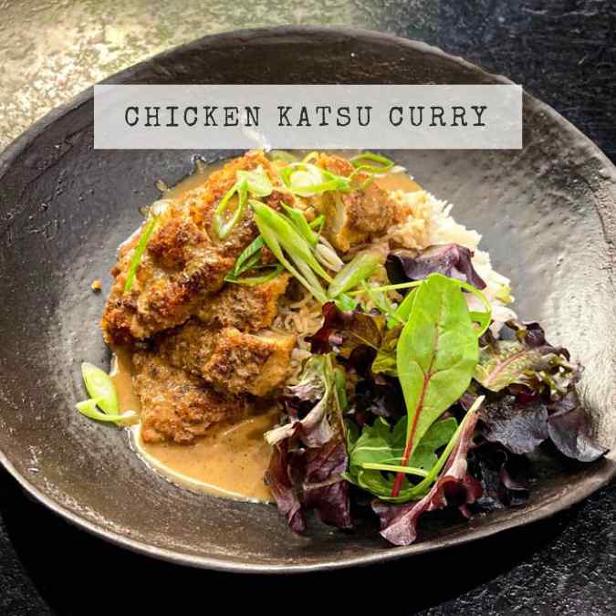 Recipe for Japanese Chicken Katsu Curry showing a a black bowl with rice, katsu chicken and katsu sauce.