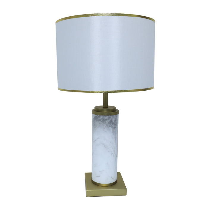 White marble cylinder table lamp with brass metal base and brass trim fabric shade turned off on white background