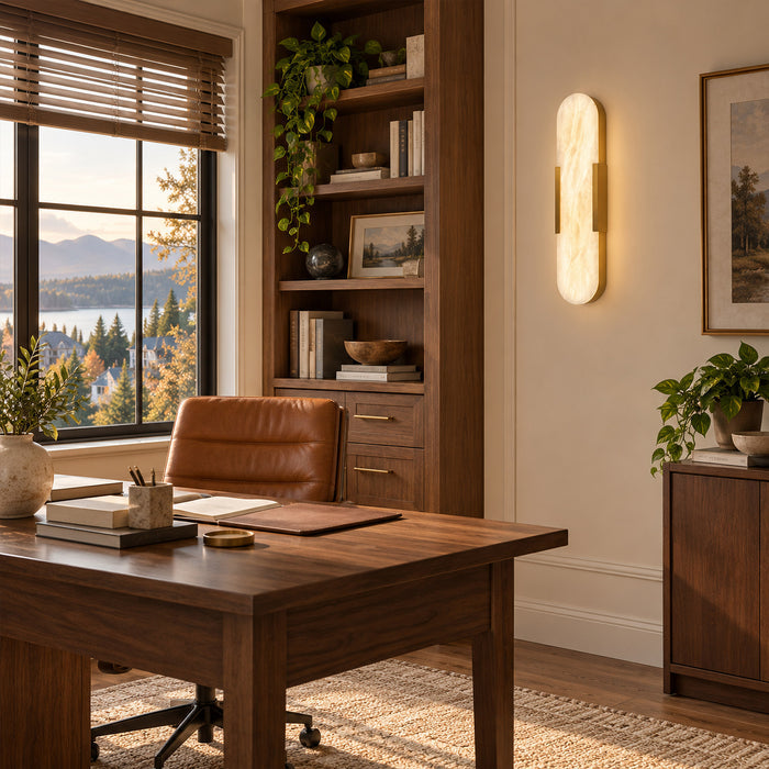 Illuminated long capsule Spanish natural alabaster wall sconce beside wooden bookshelf in home office study room