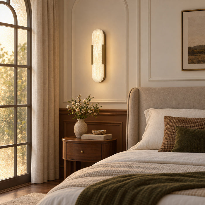 Glowing capsule Spanish natural alabaster wall sconce mounted beside a cozy bed in elegant bedroom
