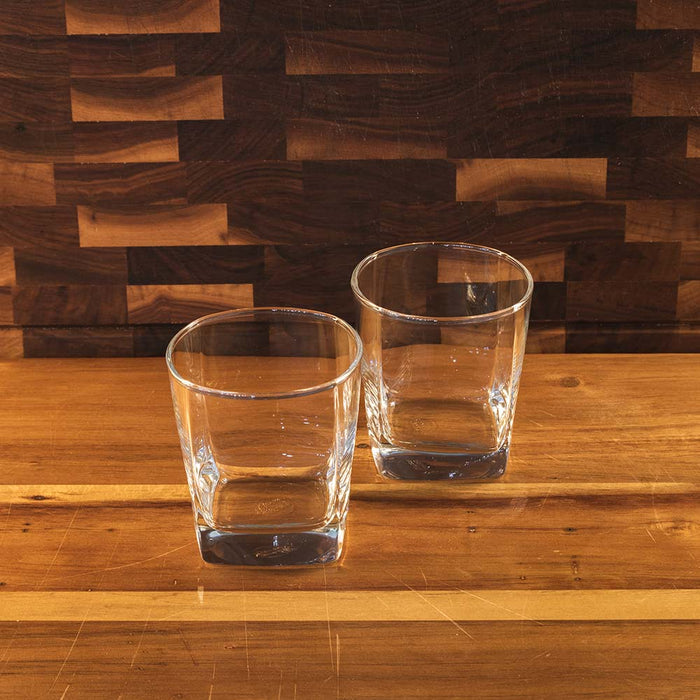 Two rocks glasses on polished wooden bar.