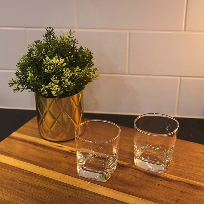 Two old fashioned cocktail glasses on wood serving board.