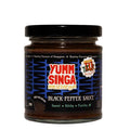 A jar of Yumm Singa black pepper sauce with black, blue and red branding, pictured on a white background